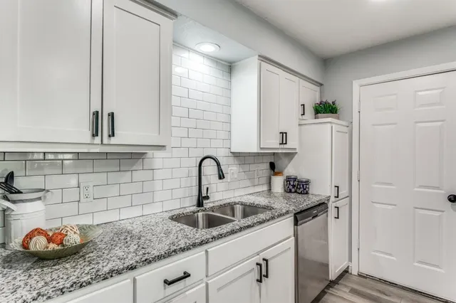 a kitchen with stainless steel appliances granite countertop a sink and a white wooden cabinets