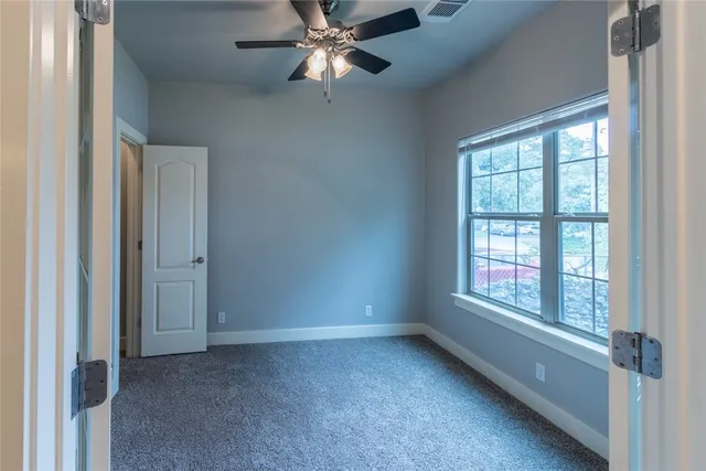 an empty room with windows and fan