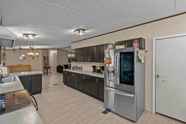 a large kitchen with stainless steel appliances kitchen island granite countertop a refrigerator a stove a sink dishwasher and white cabinets with wooden floor