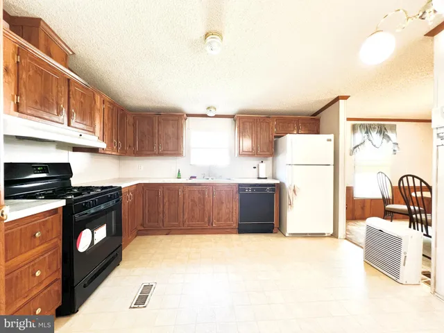 a kitchen with a refrigerator a stove a sink dishwasher and wooden cabinets with wooden floor