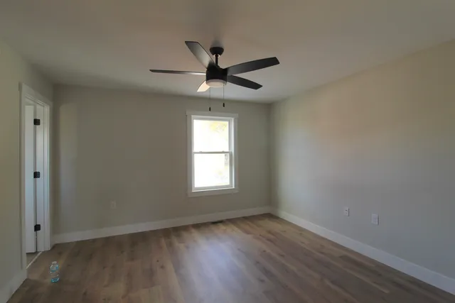 a view of an empty room with wooden floor and a window