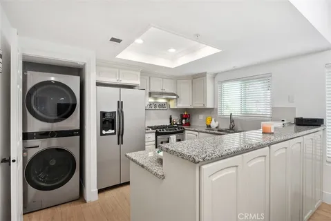 a kitchen with stainless steel appliances granite countertop a sink a stove a refrigerator cabinets and a counter top space