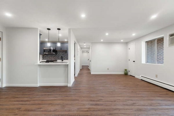 64 Main Street, Unit 53B Stoneham, MA 02180 - Photo 15 of 36 an empty room with wooden floor and a kitchen
