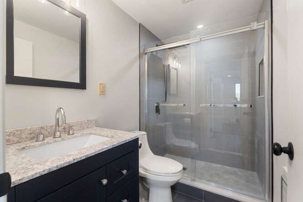 64 Main Street, Unit 53B Stoneham, MA 02180 - Photo 33 of 36 a bathroom with a shower sink vanity mirror and toilet