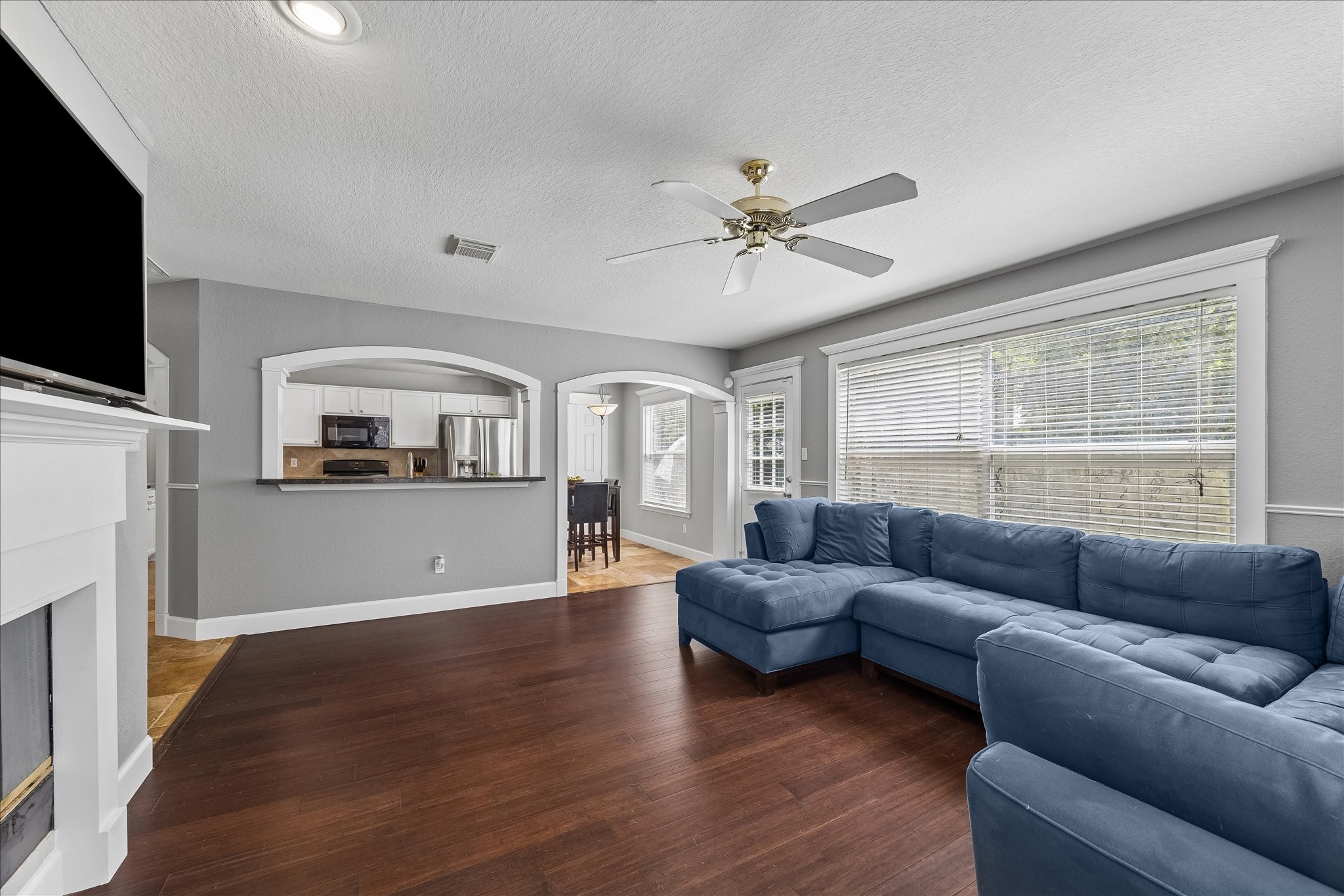 23234 Grand Rapids Lane Spring, TX 77373 - Photo 14 of 30 Generously sized living room with a cozy fireplace, rich wood flooring, and an open view into the kitchen - ideal for gatherings.