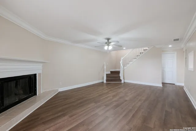 an empty room with wooden floor fireplace and windows