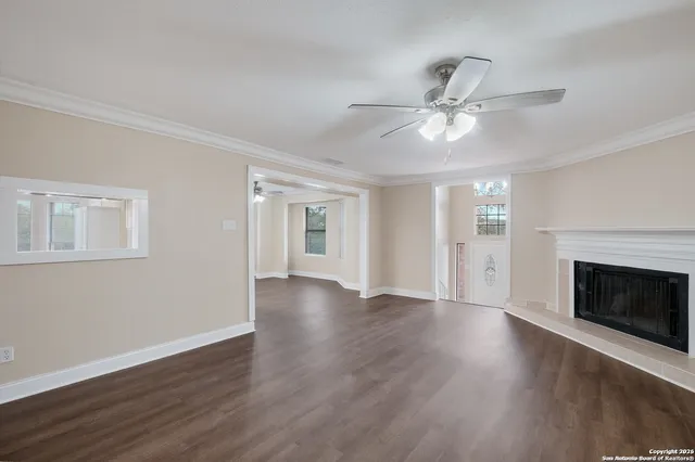 a view of an empty room with wooden floor fireplace and a window