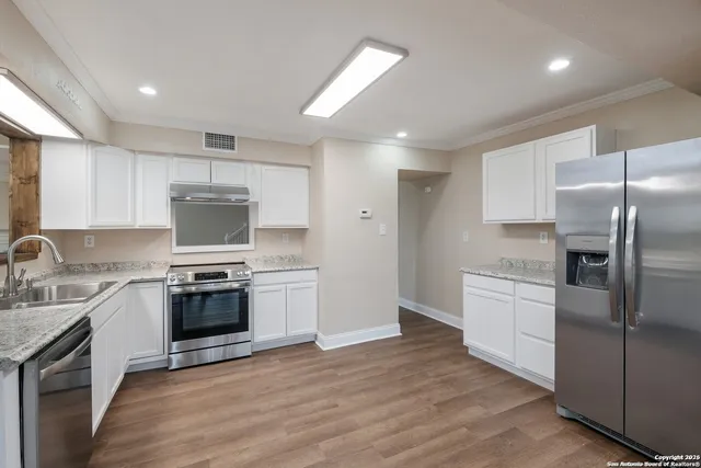 a kitchen with stainless steel appliances granite countertop a stove top oven a sink and a refrigerator