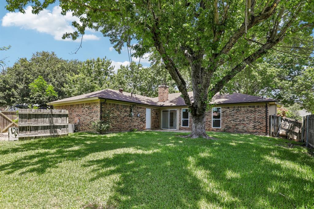 1600 South Timber Court Benbrook, TX 76126 - Photo 24 of 30 Spacious backyard featuring a large mature tree providing natural shade, a full brick exterior, a sliding glass door, and multiple windows