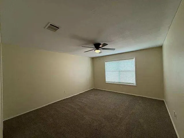 an empty room with a window and a ceiling fan