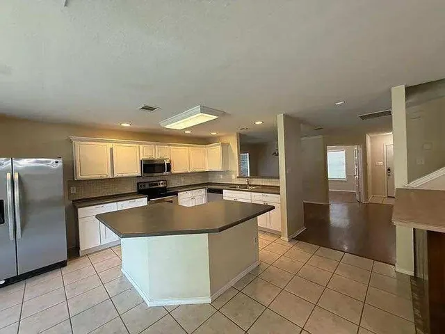 a large kitchen with kitchen island a sink a counter and a refrigerator