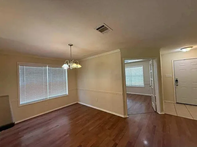 an empty room with wooden floor cabinet and windows