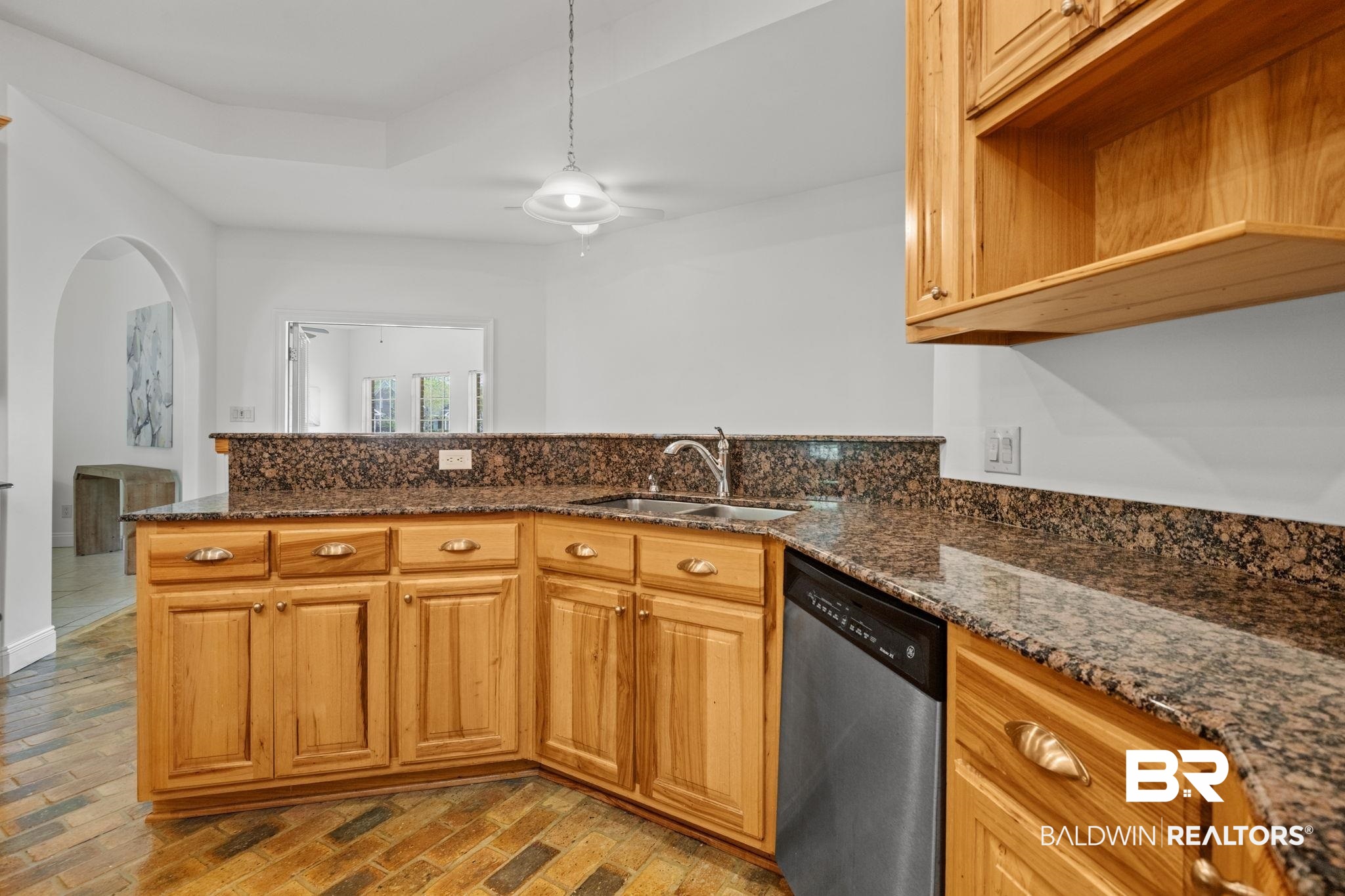 29634 St George Street Daphne, AL 36526 - Photo 23 of 47 Kitchen with brick flooring, dishwasher, dark stone counters, arched walkways, and wood finish cabinetry