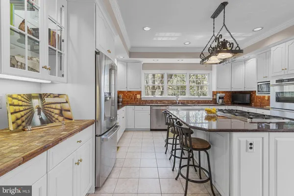 a spacious bedroom with a bed a chandelier and dresser