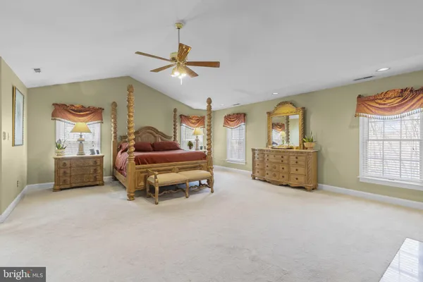 a view of a white house next to a yard with big trees