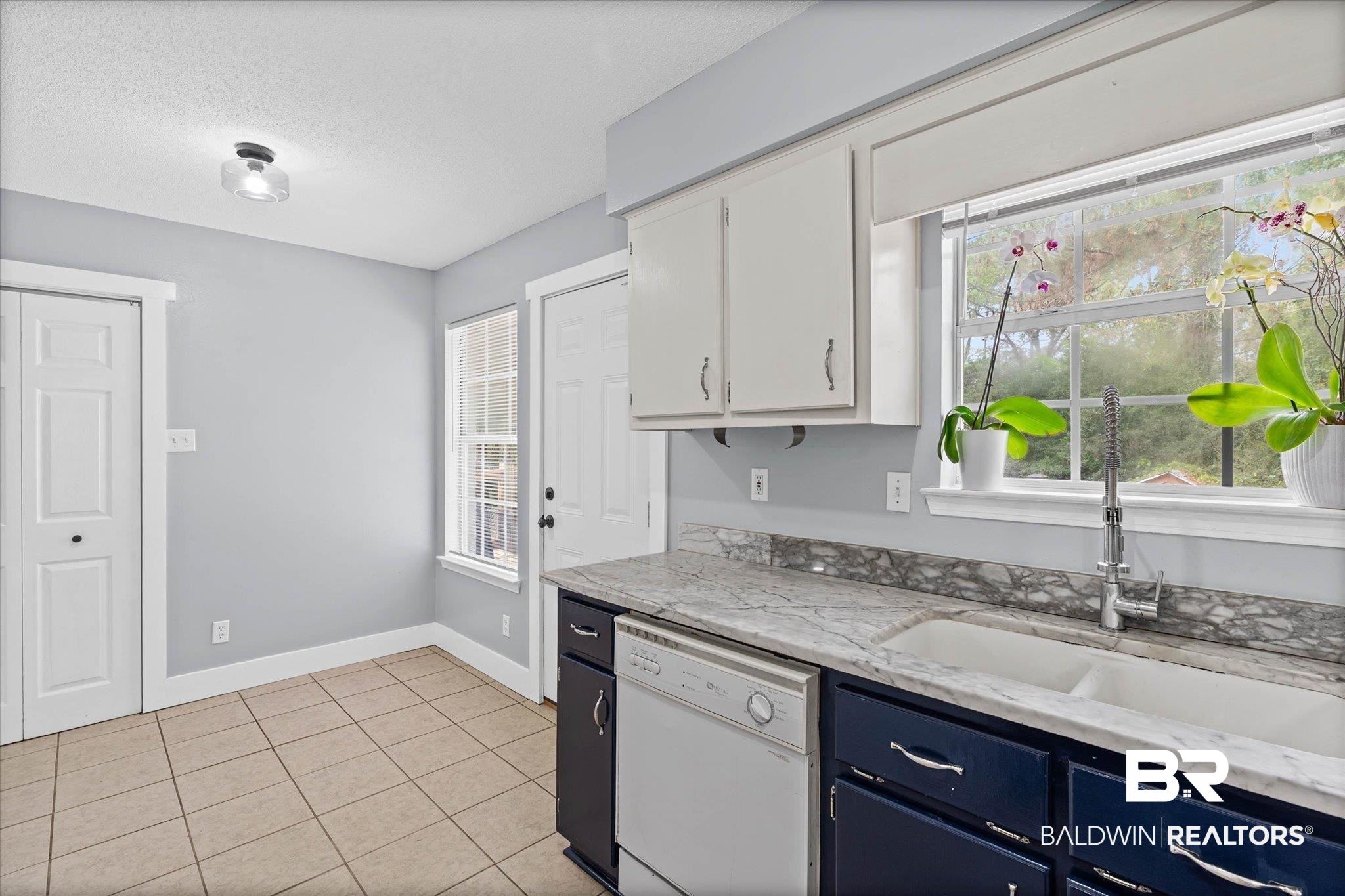1849 Ranch House Drive Semmes, AL 36575 - Photo 10 of 23 Kitchen with white dishwasher, light tile patterned flooring, light stone countertops, blue cabinets, and a textured ceiling