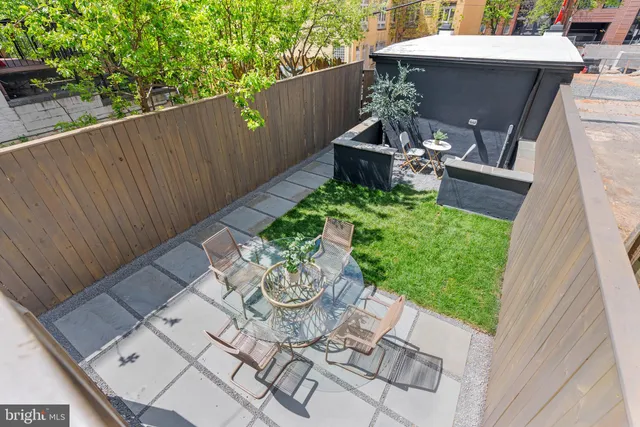 a view of a cafe with a couple of people seating under an umbrella
