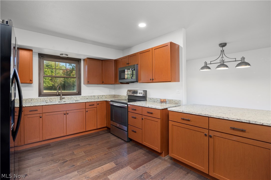 6760 Mason Road Berlin Heights, OH 44814 - Photo 12 of 49 Kitchen with electric range, brown cabinets, light stone countertops, dark wood-style flooring, and black fridge