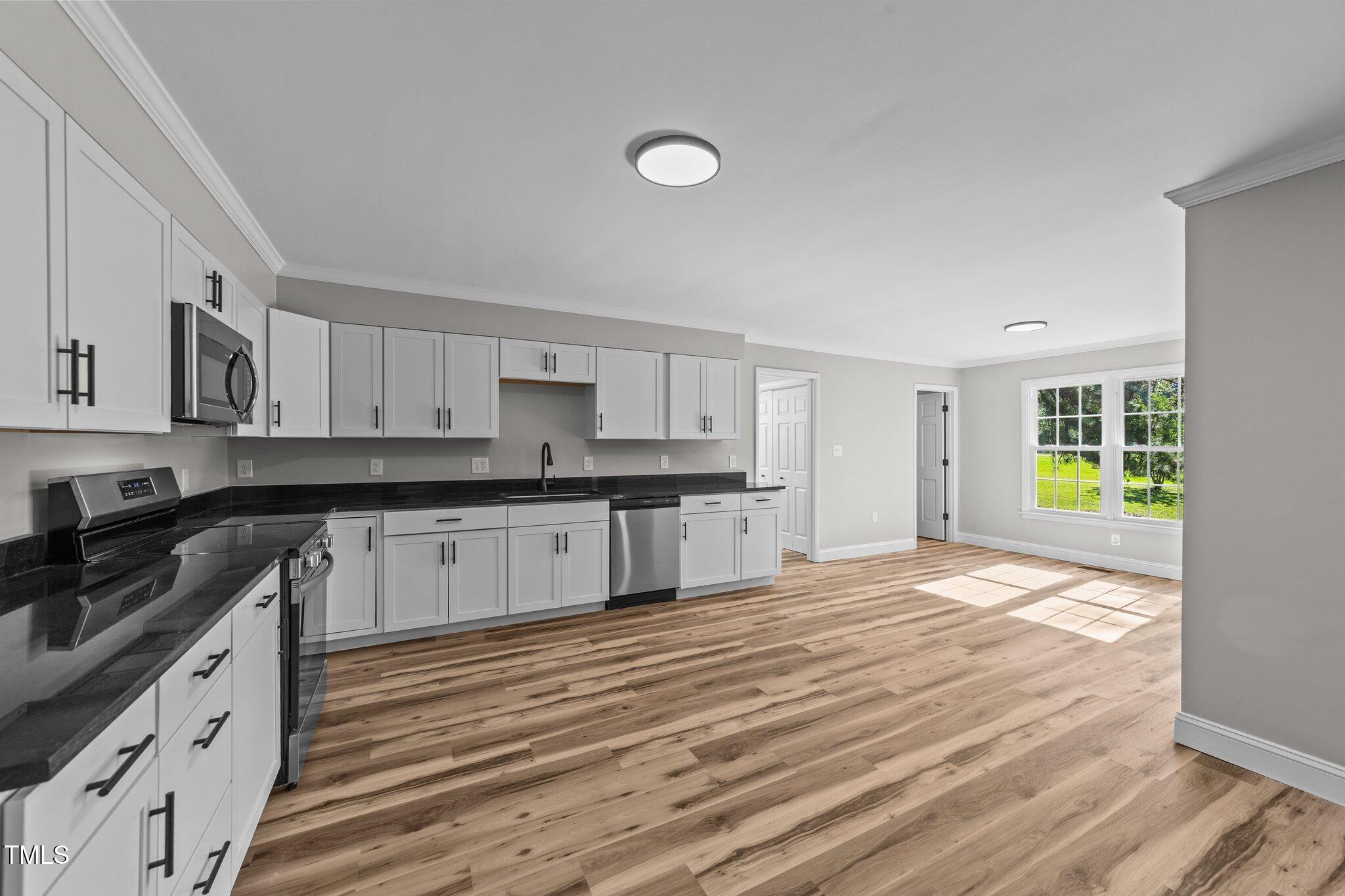 620 Richardson Road Zebulon, NC 27597 - Photo 17 of 52 a kitchen with granite countertop a stove a sink and white cabinets