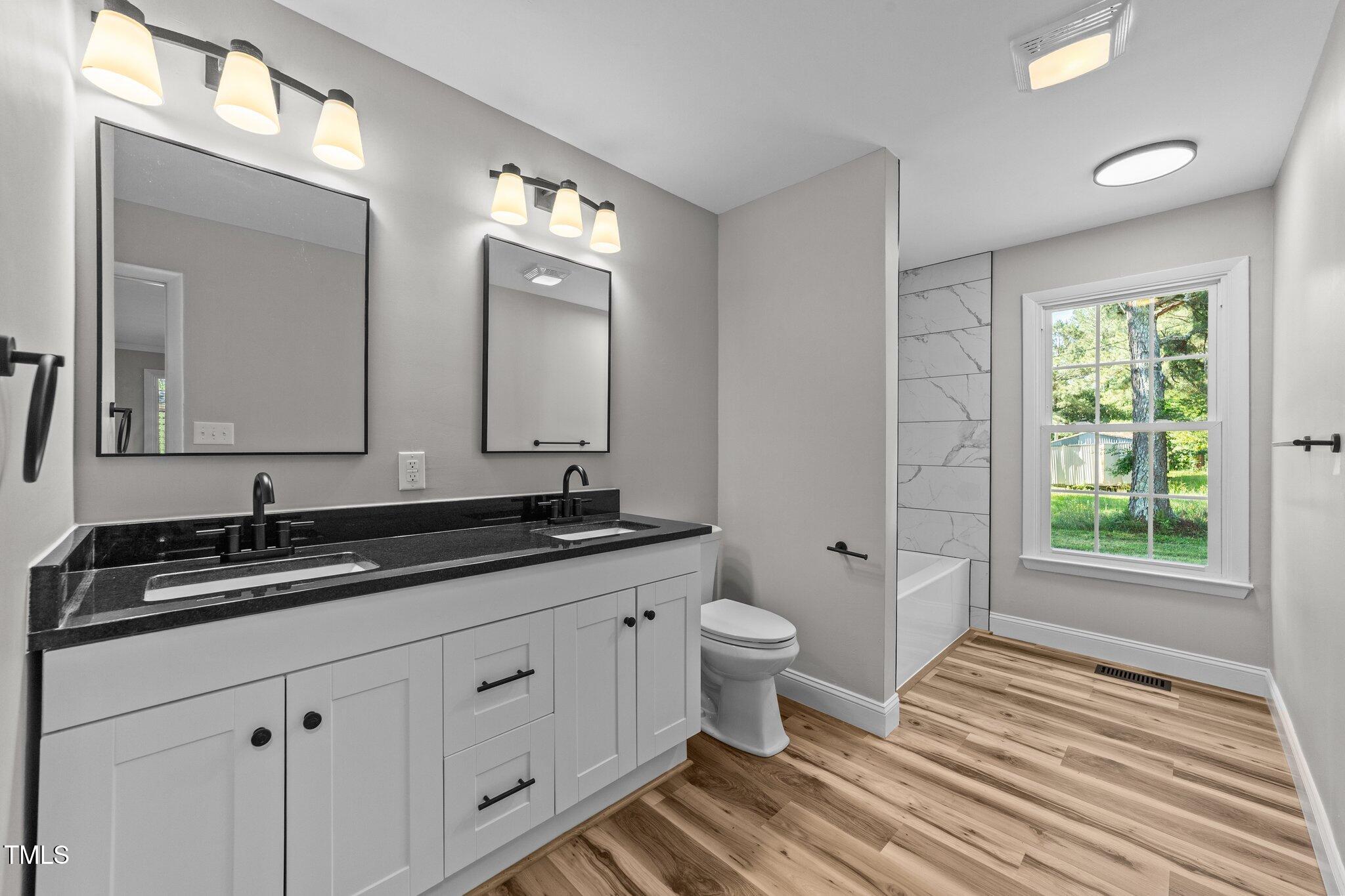 620 Richardson Road Zebulon, NC 27597 - Photo 26 of 52 a bathroom with a double vanity sink a mirror and a bathtub