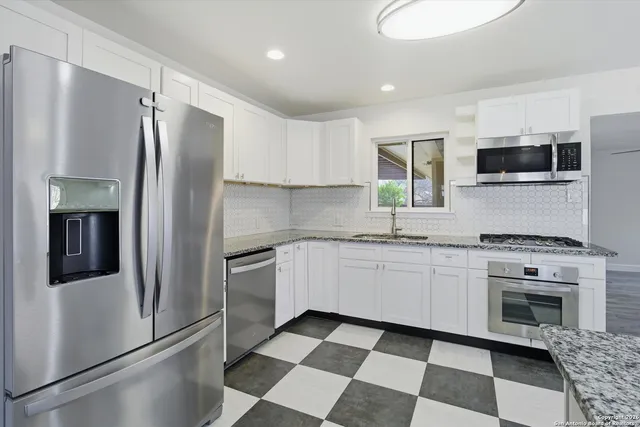 a kitchen with stainless steel appliances granite countertop a refrigerator sink and stove