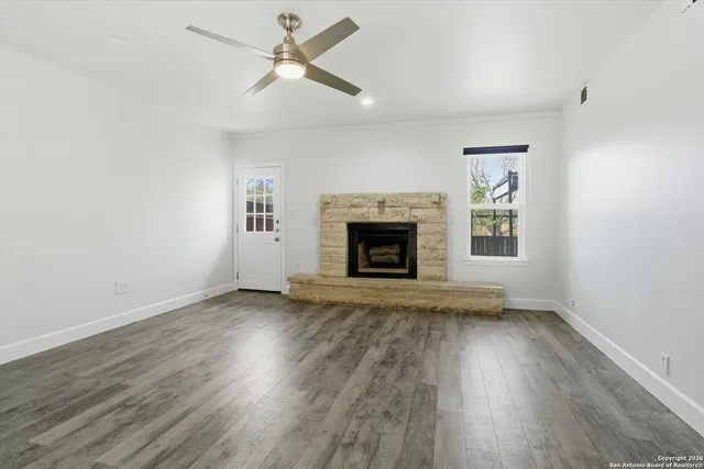 an empty room with wooden floor fireplace and a window