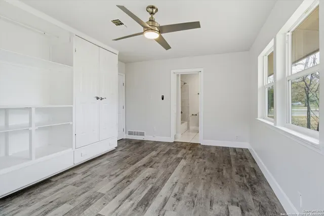 a view of empty room with wooden floor and fan