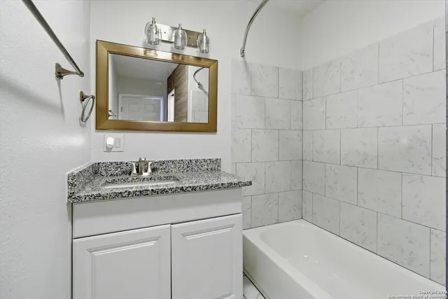 a bathroom with a granite countertop sink mirror vanity and bathtub