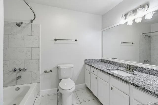 a bathroom with a granite countertop sink a toilet and bathtub