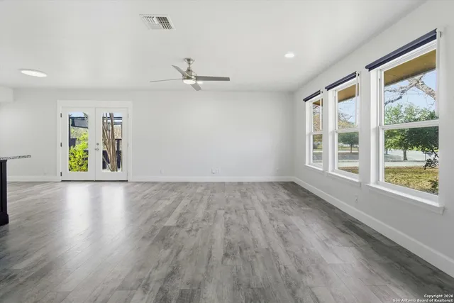 a view of an empty room with a window and wooden floor