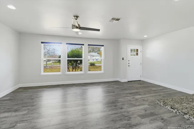 a view of an empty room with wooden floor and a window