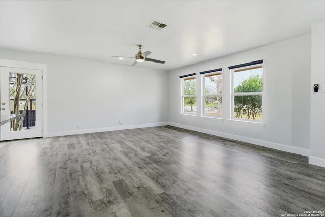 a view of an empty room with wooden floor and a window