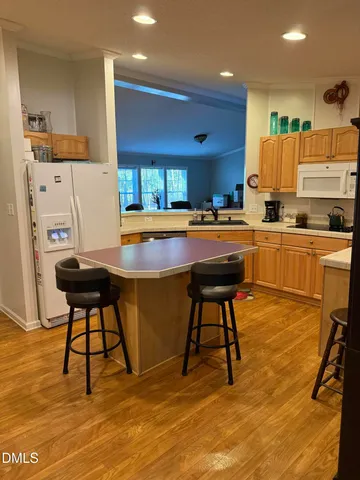 a kitchen with stainless steel appliances kitchen island granite countertop dining table chairs sink and cabinets