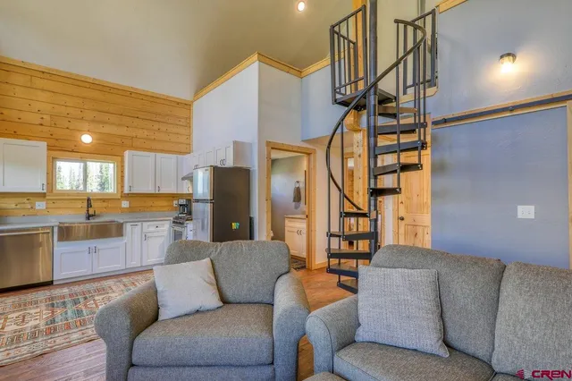 a living room with furniture kitchen view and a chandelier