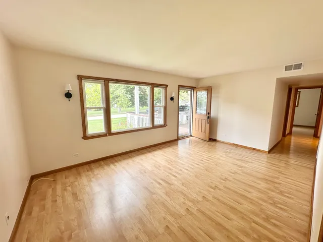 a view of an empty room with window and wooden floor
