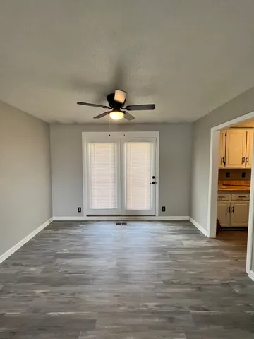 a view of an empty room with window and wooden floor