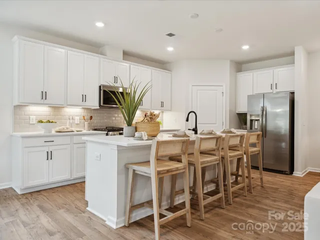 a kitchen with stainless steel appliances kitchen island granite countertop a table chairs sink and cabinets