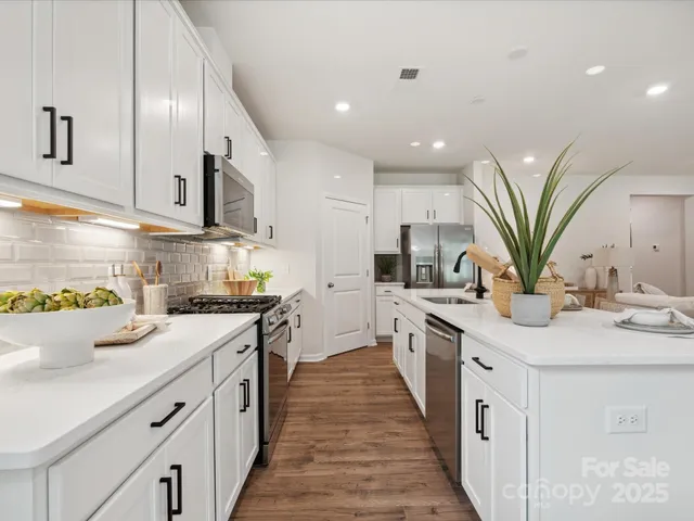 a kitchen with stainless steel appliances kitchen island granite countertop a sink a stove top oven a counter space and cabinets