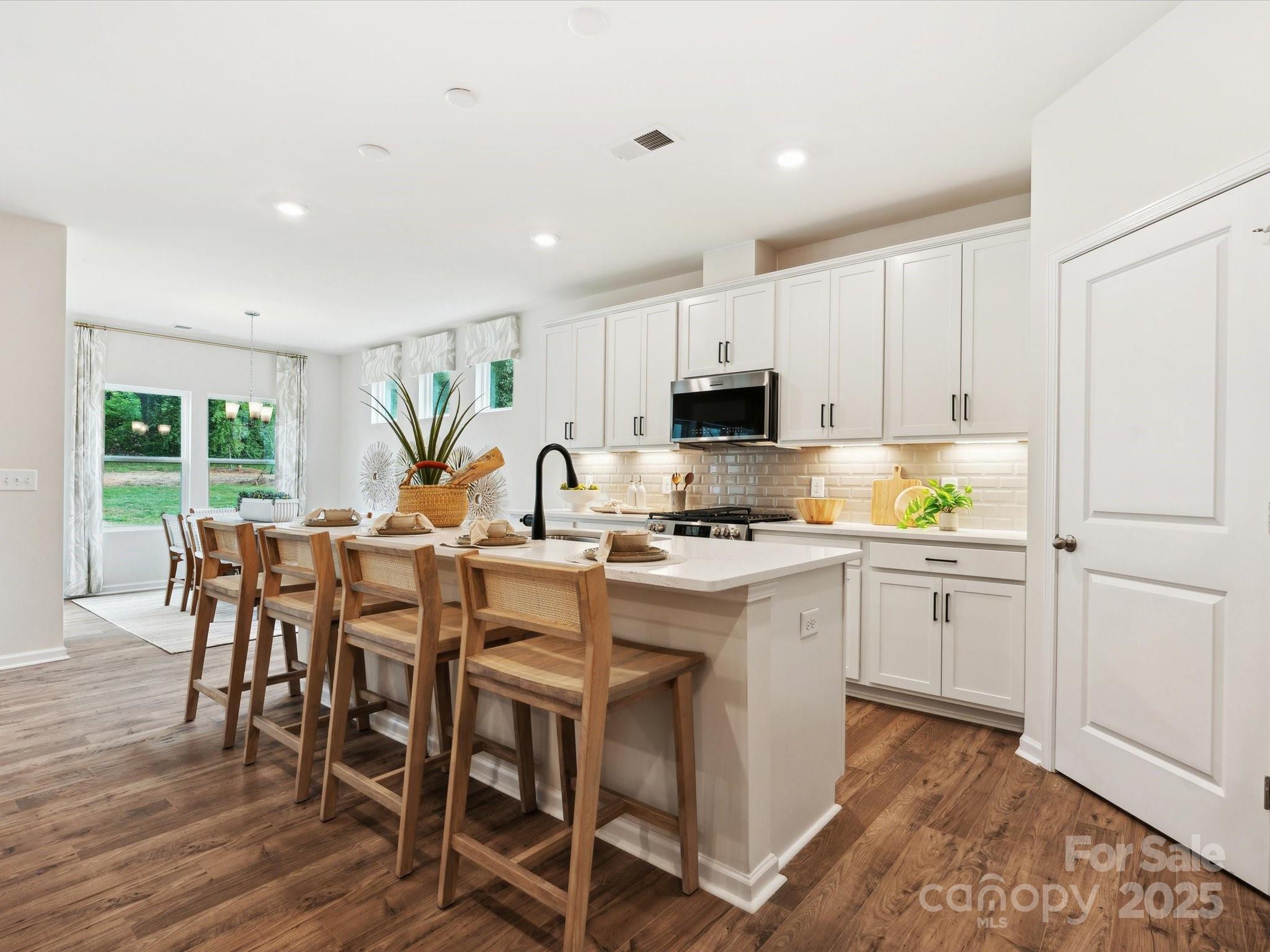 2012 Rosefield Court Matthews, NC 28104 - Photo 4 of 14 a kitchen with microwave a sink dishwasher a dining table and chairs with wooden floor