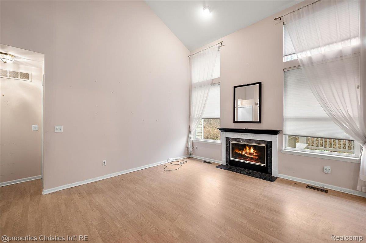 955 Rikki Ann Court Wixom, MI 48393 - Photo 24 of 54 Unfurnished living room featuring light wood-type flooring, vaulted ceiling, and a fireplace