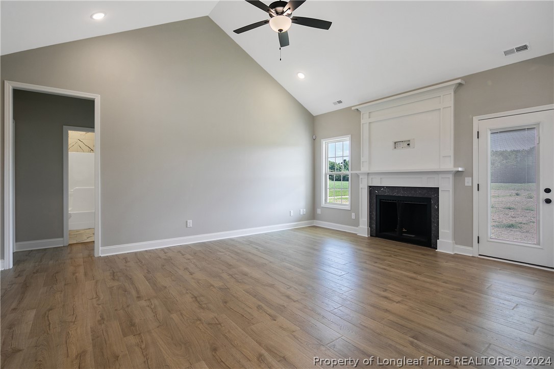 175 Spring Branch Road Tar Heel, NC 28392 - Photo 11 of 50 an empty room with wooden floor a fireplace and windows