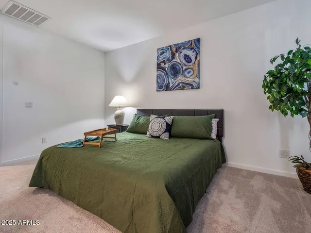 a bed sitting in a bedroom next to a window and a potted plant