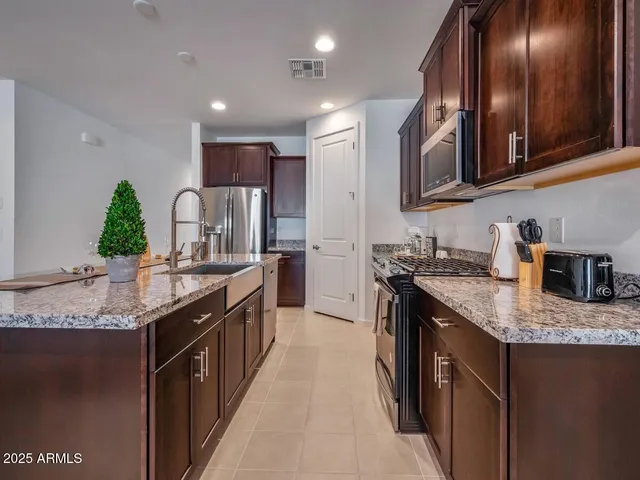 a kitchen with stainless steel appliances granite countertop a sink a stove and a refrigerator