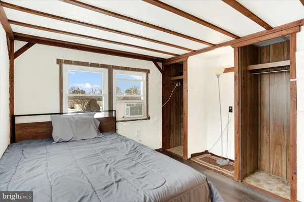 a bedroom with a bed and a window with wooden floor
