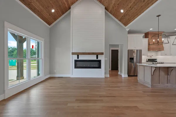 a view of an empty room with kitchen and a window
