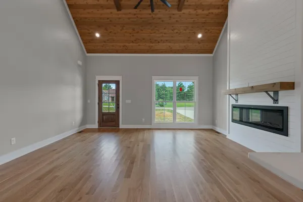 an empty room with wooden floor fireplace and windows