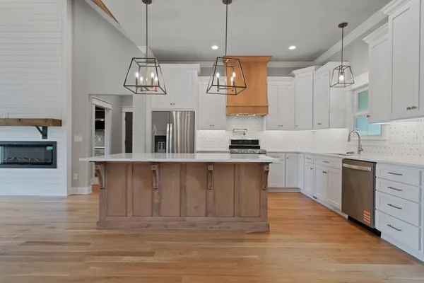 a large kitchen with stainless steel appliances kitchen island granite countertop a stove a sink and a refrigerator