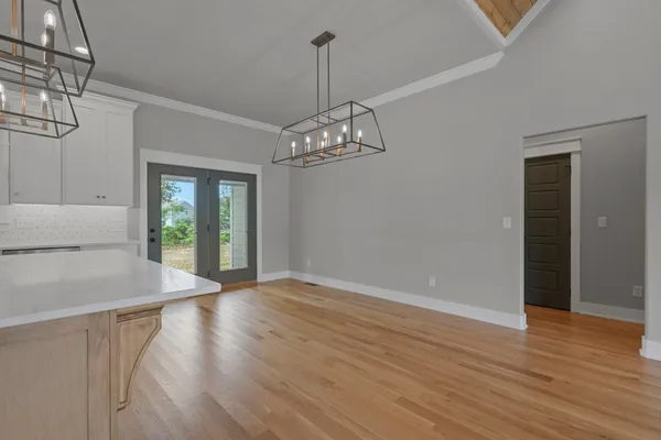 a view of a room with wooden floor chandelier and windows
