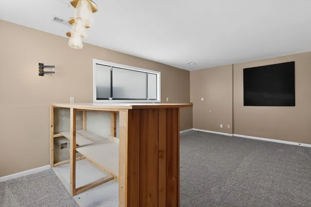 an empty room with wooden floor chandelier and windows