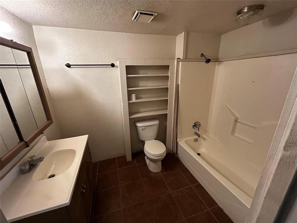 910 West Long, Unit A Stephenville, TX 76401 - Photo 31 of 39 a bathroom with a granite countertop bathtub shower sink vanity and toilet
